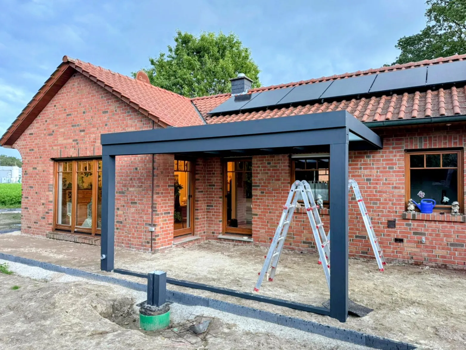 Frisch montierte Aluminium-Unterkonstruktion eines Terrassendachs an einem Klinkerhaus